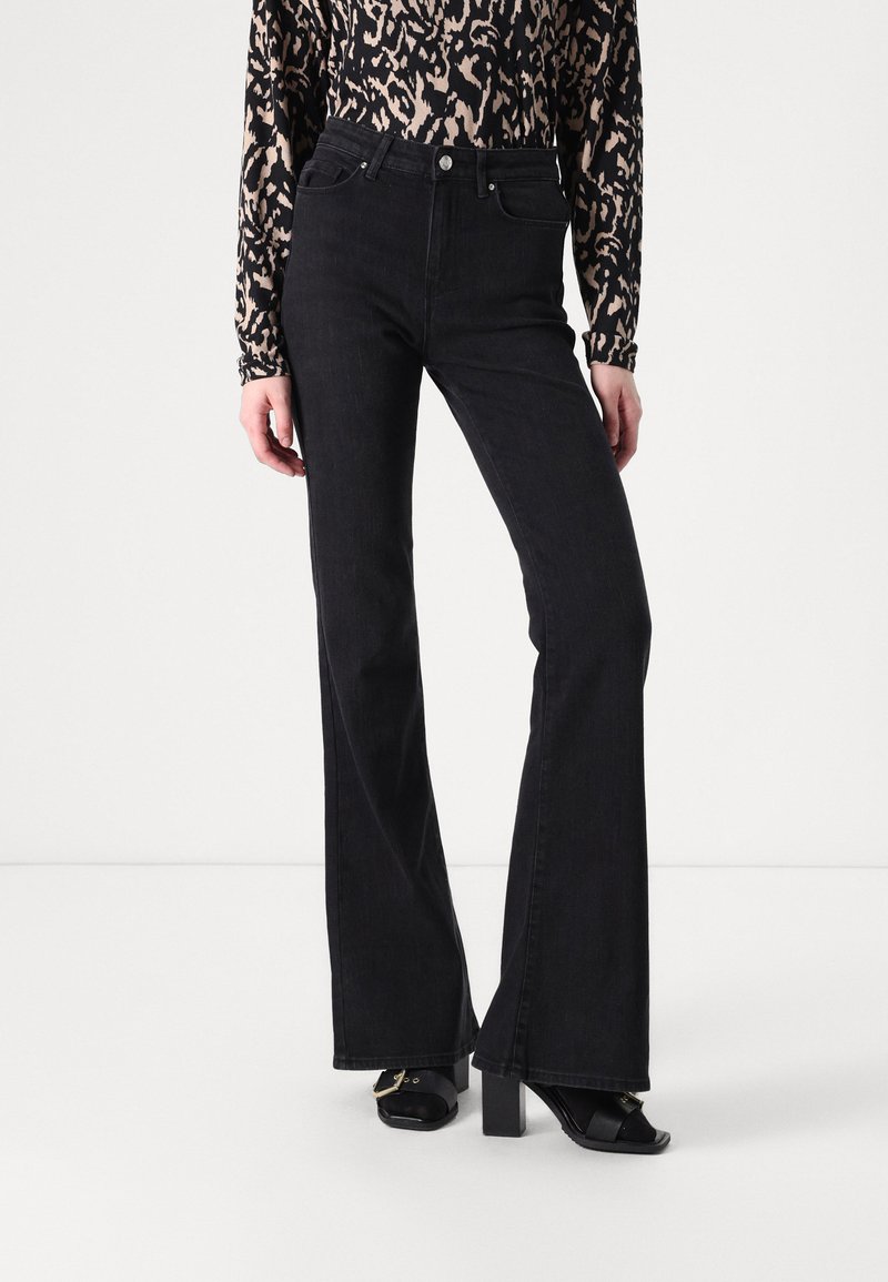 High-waisted black denim flared jeans with a textured finish, paired with a long-sleeve animal print top. Featuring a front button closure.