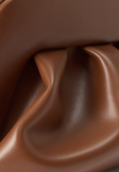 Μαλακό καφέ δερμάτινο ύφασμα με φυσικές πτυχώσεις και λεία, ελαφρώς γυαλιστερή υφή.
