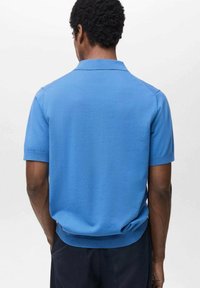 Cămașă polo de culoare albastră vibrantă, cu mâneci scurte, textură netedă, cu un guler subtil și detalii ribbate la tiv. Croială clasică și design simplu.