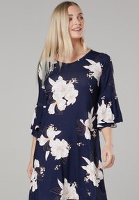 Navy floral dress with white and peach flowers, flared sleeves, round neckline, flowing fabric, features botanical prints.