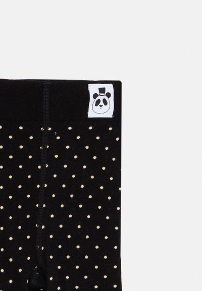 Μαύρο ύφασμα με μικρές λευκές κουκίδες και ραμμένο λευκό πατσαβούρι που απεικονίζει ένα πρόσωπο αρκούδας πάντα με καπέλο ψηλό στην επάνω άκρη.