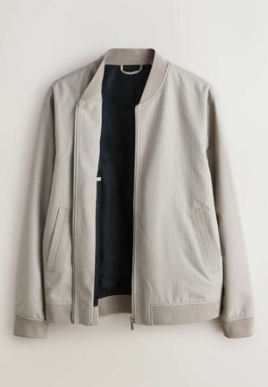 Vaaleanharmaa bomber-takki, jossa on teksturoitu ulkopinta, resorit hihansuissa ja musta sisäpinta. Takissa on sivutaskut ja eteen vetoketjullinen suljenta.