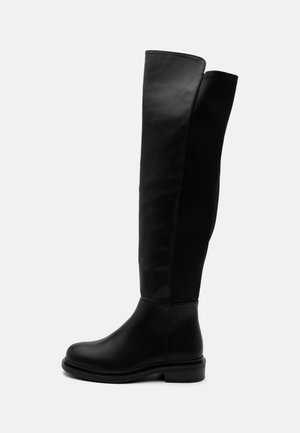 Botte noire en cuir montant jusqu'au genou avec bout arrondi, petit talon bloc et tige lisse s'étendant juste au-dessus du genou, vue de profil.