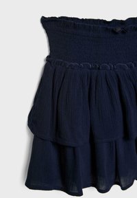 Jupe en bleu marine à volants, fabriquée en tissu texturé avec une taille froncée. L'ourlet est doux et présente un détail de volants froncés.