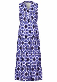 Vestido maxi en estampado geométrico morado y blanco, sin mangas, con escote en V, diseño de volantes y textura suave.