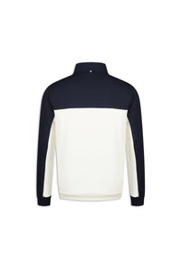 Pull à manches longues en crème et bleu marine, avec un col montant, une texture douce et des blocs de couleur contrastante au dos.