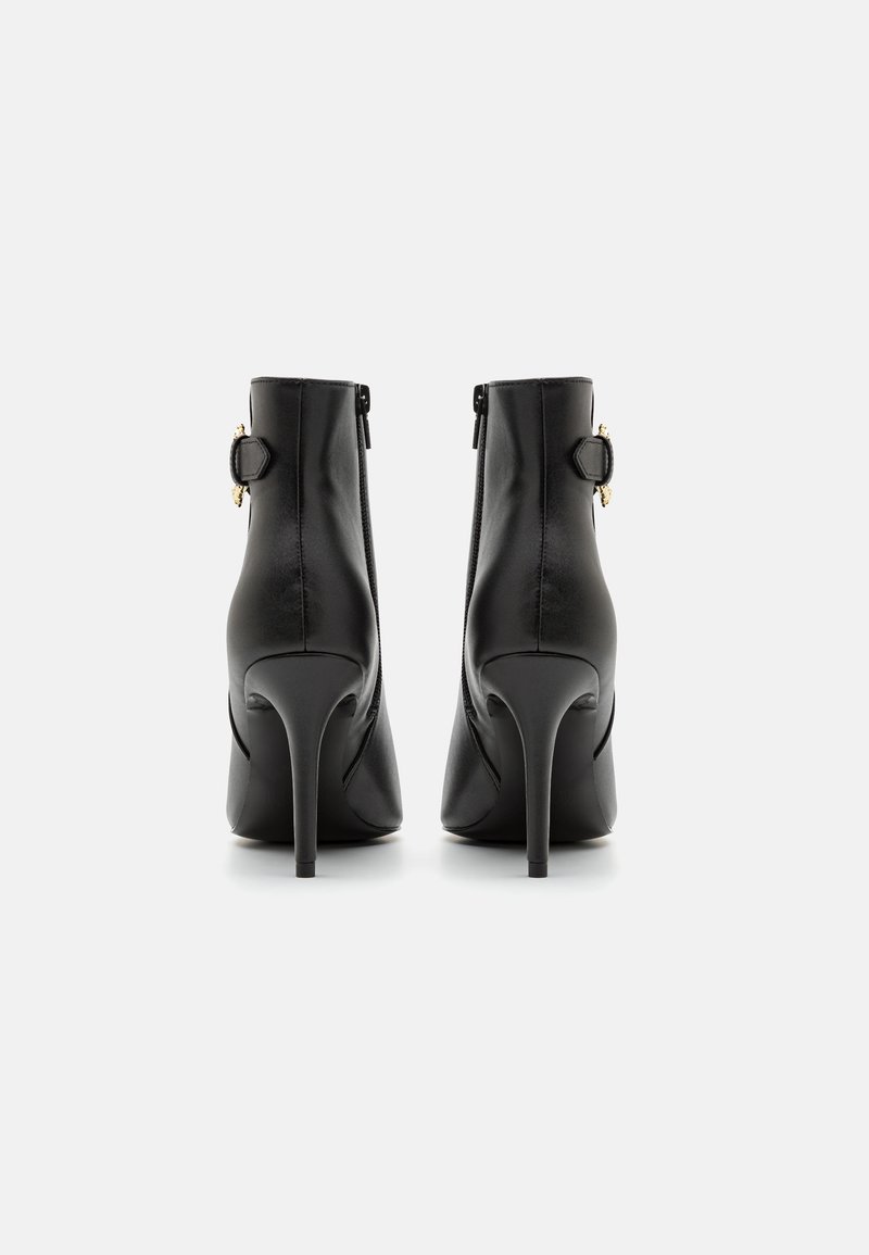 Stivaletti alla caviglia in pelle ecologica nera con punta affusolata, tacco a stiletto, cerniere laterali e dettagli in metallo dorato. Texture liscia in tutto.