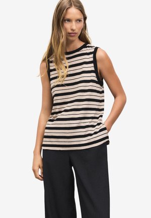 Ærmeløs top med striber i beige og sort bomuld med rund halsudskæring og løs pasform; model iført sorte bukser med vide ben.