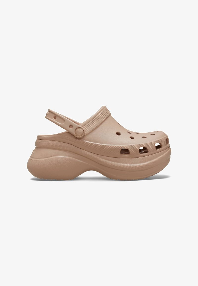 Beige Clogs mit einer stabilen Sohle, ausgestattet mit Belüftungslöchern, einem Hinterriemen und einer glatten, matten Oberfläche. Rundes Zehendesign.