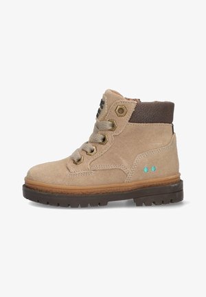 Beige suède enkellaars met bruine leren accenten, gouden oogjes en turquoise stippen. Heeft een gestructureerde zool voor grip.