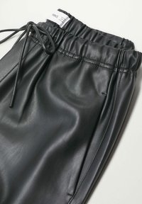 Pantalons en similicuir noir avec une taille élastique, détail de cordon de serrage et texture lisse, comportant des accents cousus et sans poches visibles.