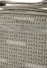 Borsa grigia in materiale texturizzato con loghi ripetuti a opacità variabile. Cerniera decorativa che corre orizzontalmente sulla parte anteriore.