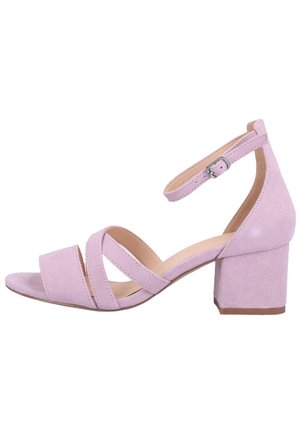 Lichtroze suede blokhak sandalen hebben een gesloten achterkant, open teen en gekruiste banden aan de voorkant, met een verstelbare enkelband.