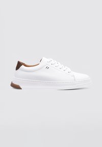 Baskets blanches en cuir avec un bout arrondi, un accent talon marron et six œillets pour les lacets. Surface texturée et semelle rembourrée.