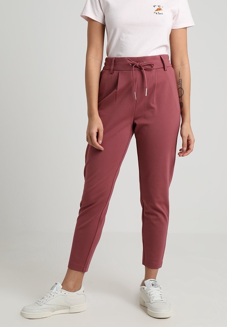 Bordeaux tapered broeken gemaakt van rekbaar materiaal, met een trekkoord in de taille, plooien en zijzakken, gecombineerd met witte sneakers.