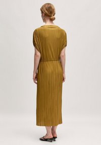 Langes, plissiertes Kleid in Senfgelb, mit kurzen Ärmeln und einem Gürtel in der Taille. Glatter, strukturierten Stoff mit fließender Silhouette.