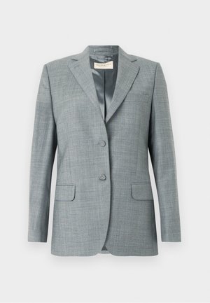 Grey plaid blazer over a black blouse, paired with dark grey jeans and black pointed flats. The outfit features sleek lines and a tailored fit.