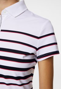 Vit polo skjorta med horisontella marinblå och röda ränder, med en klassisk krage och korta ärmar, tillverkad av strukturerad tyg.