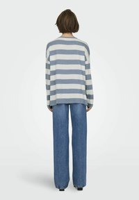 Maglietta a maniche lunghe a righe in grigio chiaro e blu, abbinata a jeans in denim a vita alta. Presenta una vestibilità comoda e cuciture delle spalle basse.