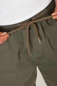 Olive green drawstring pants made of smooth fabric. Features a braided cord with copper-tone metal tips and an elastic waistband.