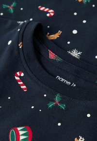 T-shirt en coton bleu marine avec des motifs festifs de cannes en sucre, de rennes, de houx et de flocons de neige. Encolure côtelée avec étiquette imprimée.