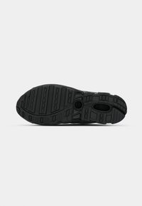 Zwarte sport schoen zool met een gestructureerd rubberen oppervlak, voorzien van opvallende groeven en cirkelvormige elementen voor verbeterde grip.