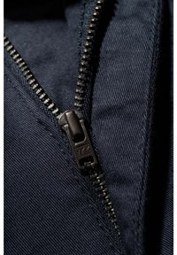 Textil azul marino con cremallera metálica de dientes de plástico y tirador, que muestra una fina textura acanalada y bordes estrechamente cosidos.