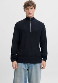Ciemnogranatowy sweter z prążkowanego dzianiny z wysokim kołnierzem i zamkiem błyskawicznym z przodu, z długimi rękawami i luźnym krojem. Lekka faktura materiału.