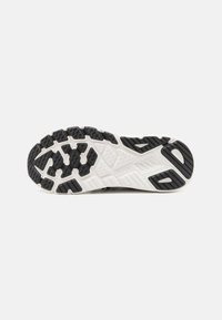 Semelle en caoutchouc noir de chaussure de sport avec un motif de relief distinctif et une semelle intermédiaire blanche texturée pour une meilleure adhérence et durabilité.