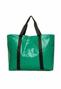 Liela zaļa sintētiska iepirkumu soma ar spīdīgu virsmu, kurai ir divi melni auduma rokturi un taisnstūra forma.
