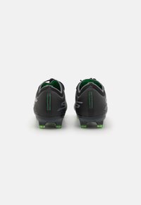Crampons de soccer noirs avec une finition texturée, accents verts et un profil bas. Présente cinq crampons moulés pour une traction sur les surfaces en herbe.