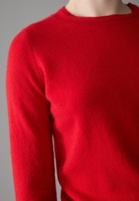 Red wool sweater with a crew neck, long sleeves, and a soft texture, highlighting a smooth finish and vibrant color.
