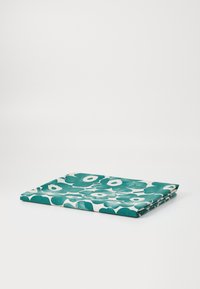 Tessuto piegato con un motivo floreale in turchese e bianco. La texture appare morbida, con forme di fiori audaci e rotonde sparse ovunque.