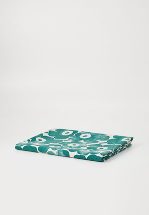 Folded fabric with a floral pattern in teal and white. The texture appears soft, featuring bold, round flower shapes throughout.