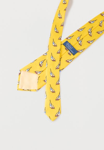Κίτρινη μεταξωτή γραβάτα με σχέδιο μπλε και λευκών ιστιοπλοϊκών και ετικέτα Polo Ralph Lauren σε ανοιχτό φόντο.