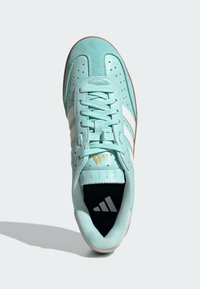 Turkusowe sneakersy wykonane z zamszu i skóry, z białymi paskami, perforowanym wzorem i brązową gumową podeszwą, z logo na wnętrzu.