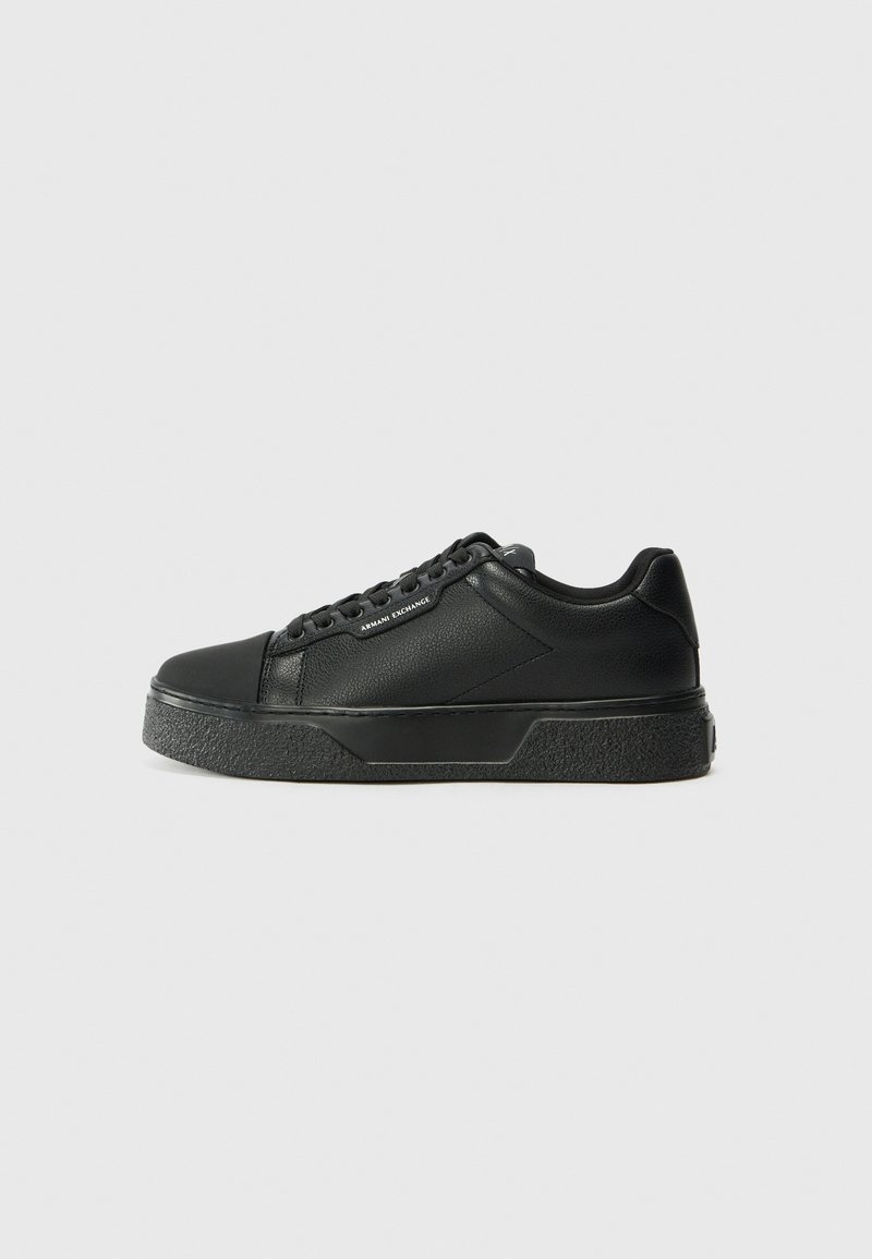 Tenis negri cu un superior din piele netedă, vârf rotund și talpă din cauciuc texturat. Prezintă un design cu șireturi și un detaliu subtil al logo-ului pe lateral.