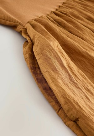 Brown dress made of lightweight, wrinkled fabric with a textured top and pleated skirt design, featuring gathered seams at the waist.