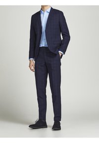 Marinblå rutigt kostym med slim fit, utrustad med en kavaj med en knapp, tillsammans med en ljusblå skjorta och svarta snörskor.