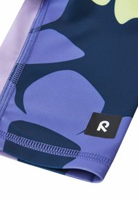 Wielokolorowe legginsy sportowe z dużymi niebieskimi i purpurowymi abstrakcyjnymi wzorami, wykonane z gładkiego materiału; posiadają dyskretną etykietę z logo w kolorze czarnym.