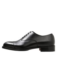 Chaussure Oxford en cuir noir avec une finition lisse, un bout rond et cinq œillets pour les lacets. Elle présente un talon bas empilé et des détails cousus.