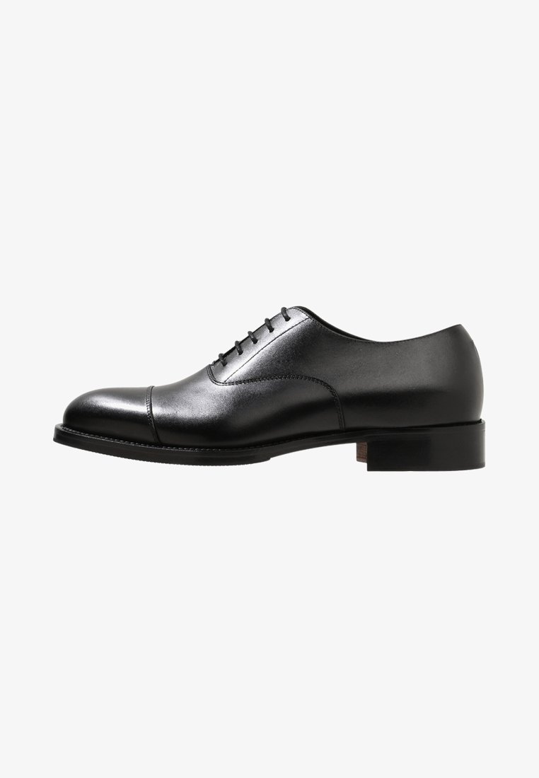 Chaussure Oxford en cuir noir avec une finition lisse, un bout rond et cinq œillets pour les lacets. Elle présente un talon bas empilé et des détails cousus.