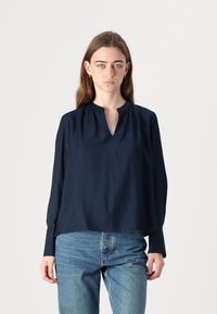 Blusa blu navy con scollatura a V e maniche lunghe, realizzata in un tessuto morbido con delicate arricciature alle spalle e una vestibilità rilassata.
