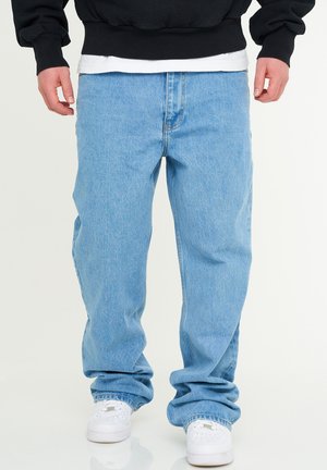 Hellblaue Denim-Jeans mit bequemer Passform, gerade geschnittenem Bein und umgeschlagenem Saum, kombiniert mit weißen Sneakers.