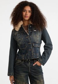 Giacca di jeans con colletto in pelliccia sintetica, dotata di tasche frontali, colore blu sbiadito e design cropped. Abbinata a pantaloni in denim coordinati.