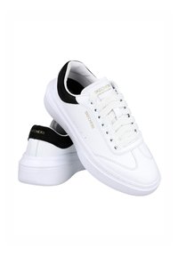Zapatillas de cuero blanco con acentos negros, diseño con cordones y una gruesa suela de goma blanca. Presenta la marca "SKECHERS" en dorado.