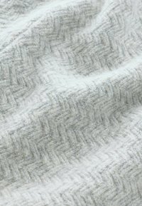 Hellgrauer gewebter Stoff mit Fischgrätenmuster. Sanfte Textur mit leichten Farbvariationen, die Tiefe und visuelles Interesse erzeugen.