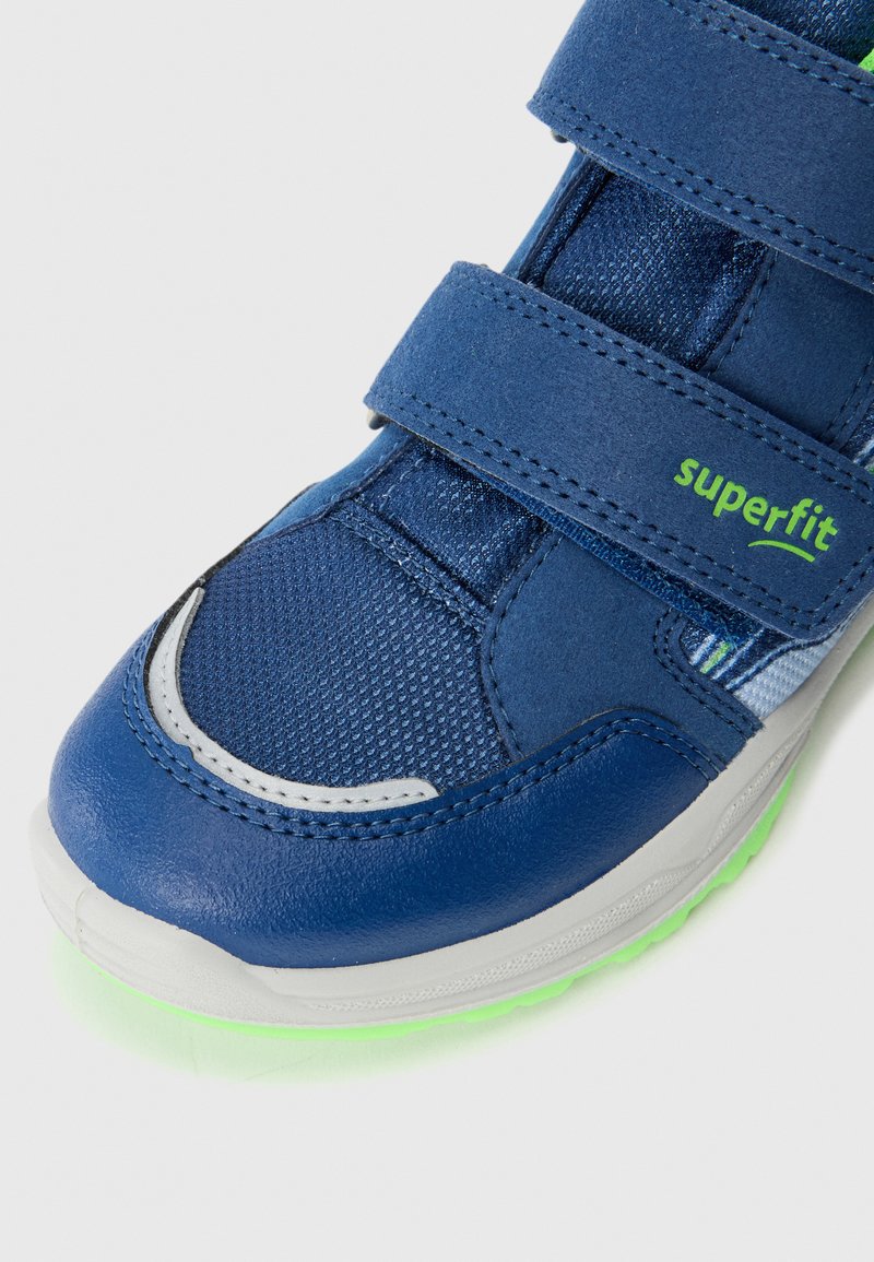 Blaue Sportschuh mit einem Obermaterial aus Mesh, doppelte Klettverschlüsse und einem grünen Akzent. Verfügt über eine Gummisohle mit strukturiertem Finish.
