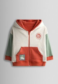 Beige capuchonvest met rits, met een oranje voorkant en groene mouwen. Voorzien van een "Stay Wild"-afbeelding en een patch met het opschrift "Top Ranger".