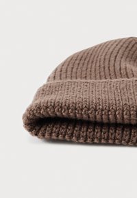 Gorro de punto marrón que muestra una textura acanalada, con un puño doblado y material de lana suave, posicionado en un ángulo para visibilidad de detalles.